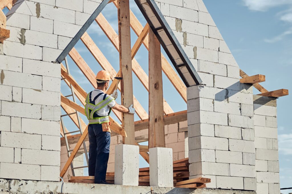 Concentrated man in safety gear building a house